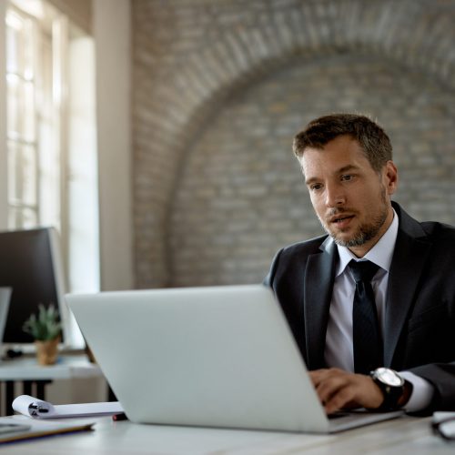 Male entrepreneur working on a computer at his office desk.
